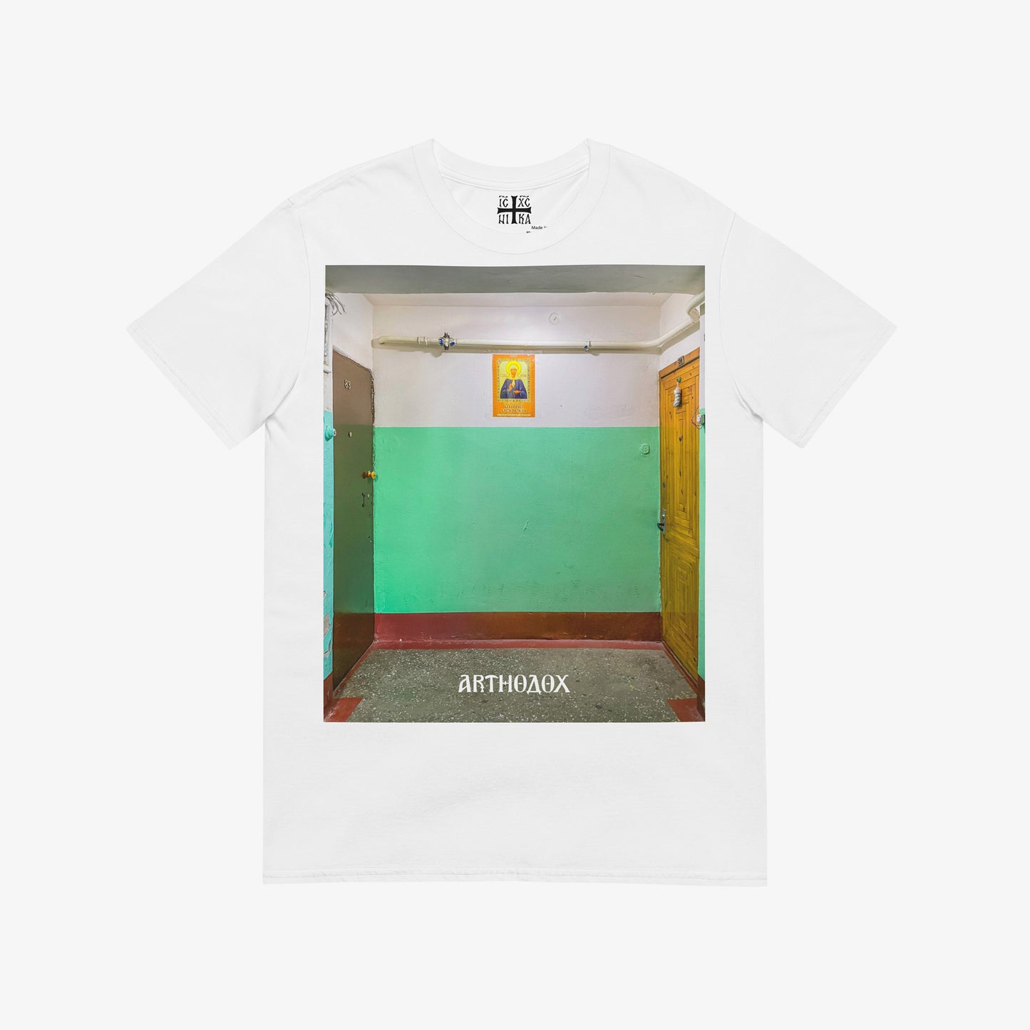White unisex T-shirt with a large print depicting a typical Russian apartment stairwell featuring an icon of Holy Blessed Matrona of Moscow on the wall. From arthodox.com